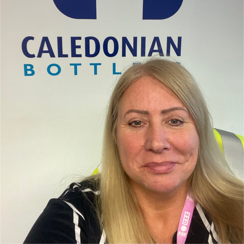 Head and shoulders image of a woman with a 'Caledonian Bottling' sign on the wall in the background.