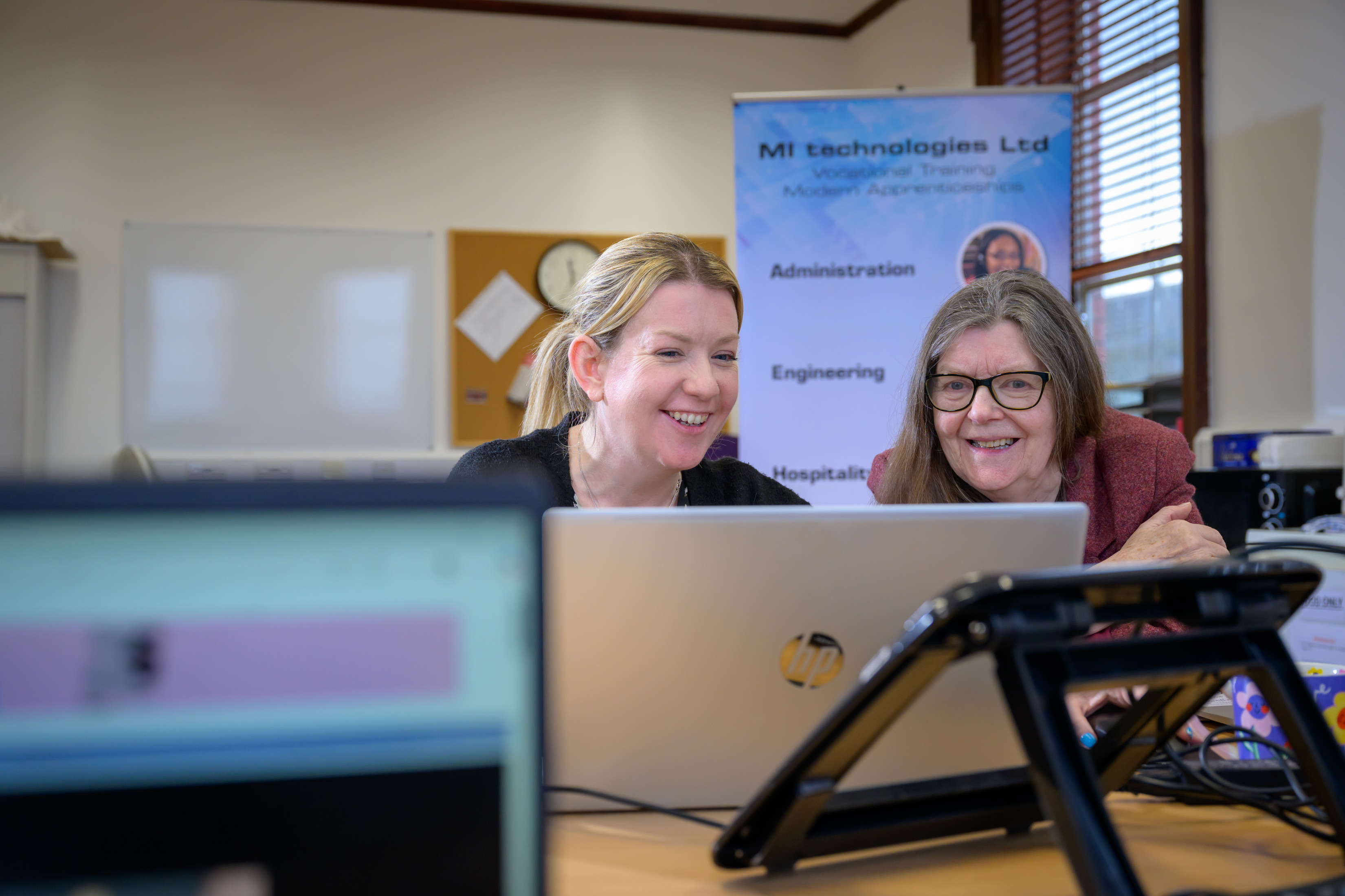 Two women look at a laptop.