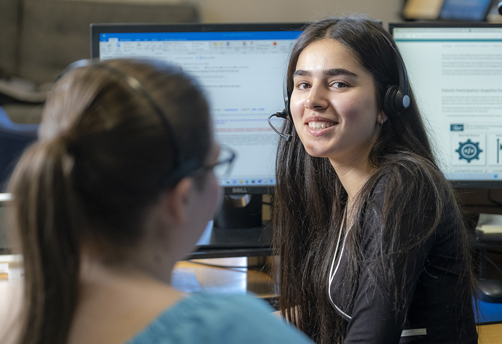 A girl smiling while viewing a course on her computer.