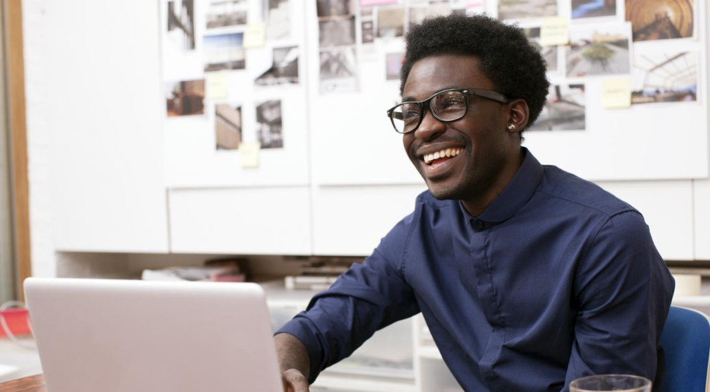 A man smiling while using a laptop.